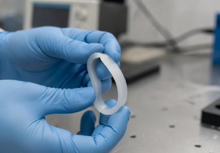 Mechanical engineer confidently bending a flexible machined plastic clip demonstrating extreme kinetic resilience.png