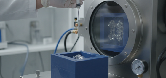 Technician injecting liquid polyurethane into a silicone cavity inside a heavy vacuum chamber