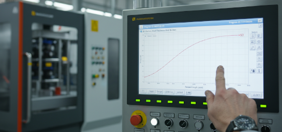 Operator adjusting 100-point parison wall thickness programming curve on a blow molding machine control panel